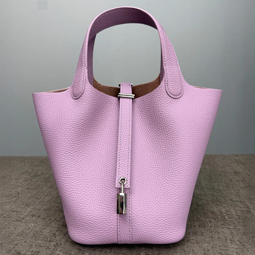A light purple genuine leather bucket bag with a vertical zipper closure and a contrasting brown lining.