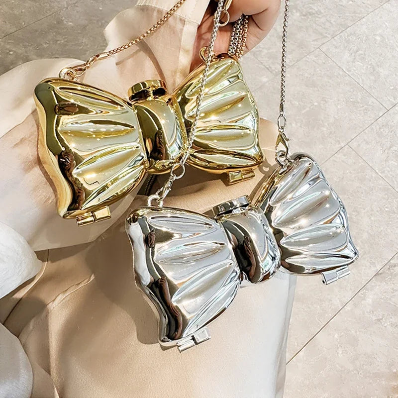 Gold and silver heart-shaped acrylic evening clutch with a chain strap being held by a hand.