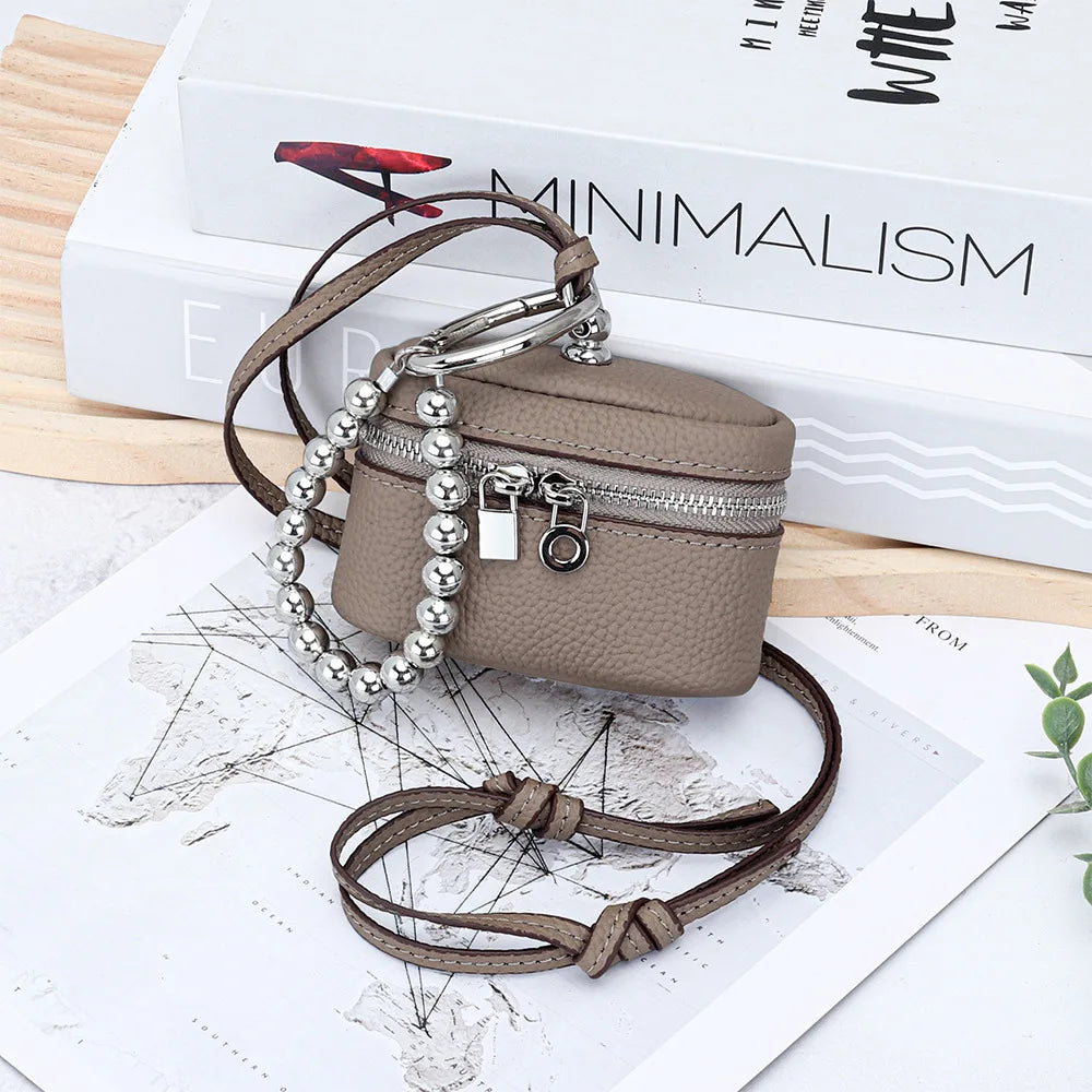 A handcrafted brown leather coin purse with a silver chain lanyard rests on a map and white background.