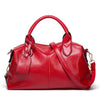 A red faux leather Boston handbag with a curved handle and flap closure is shown against a white background.