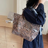 Eine Frau hält eine leopardprintierte PVC-Tasche vor einem hellen Holzschrank.