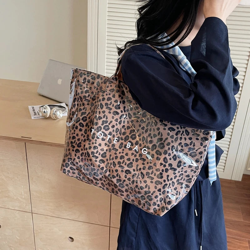 Eine Frau hält eine leopardprintierte PVC-Tasche vor einem hellen Holzschrank.
