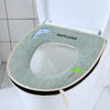 A light green plush waterproof toilet seat cover with a welcome message and a small palm leaf decoration.