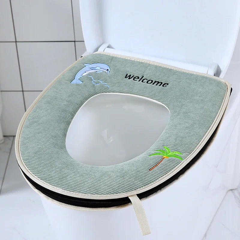 A light green plush waterproof toilet seat cover with a welcome message and a small palm leaf decoration.