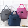 A pink insulated canvas tote bag is displayed next to a gray one on a white surface.