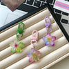 A collection of colorful resin flower keychains in green, purple, and pink hanging from metal rings.