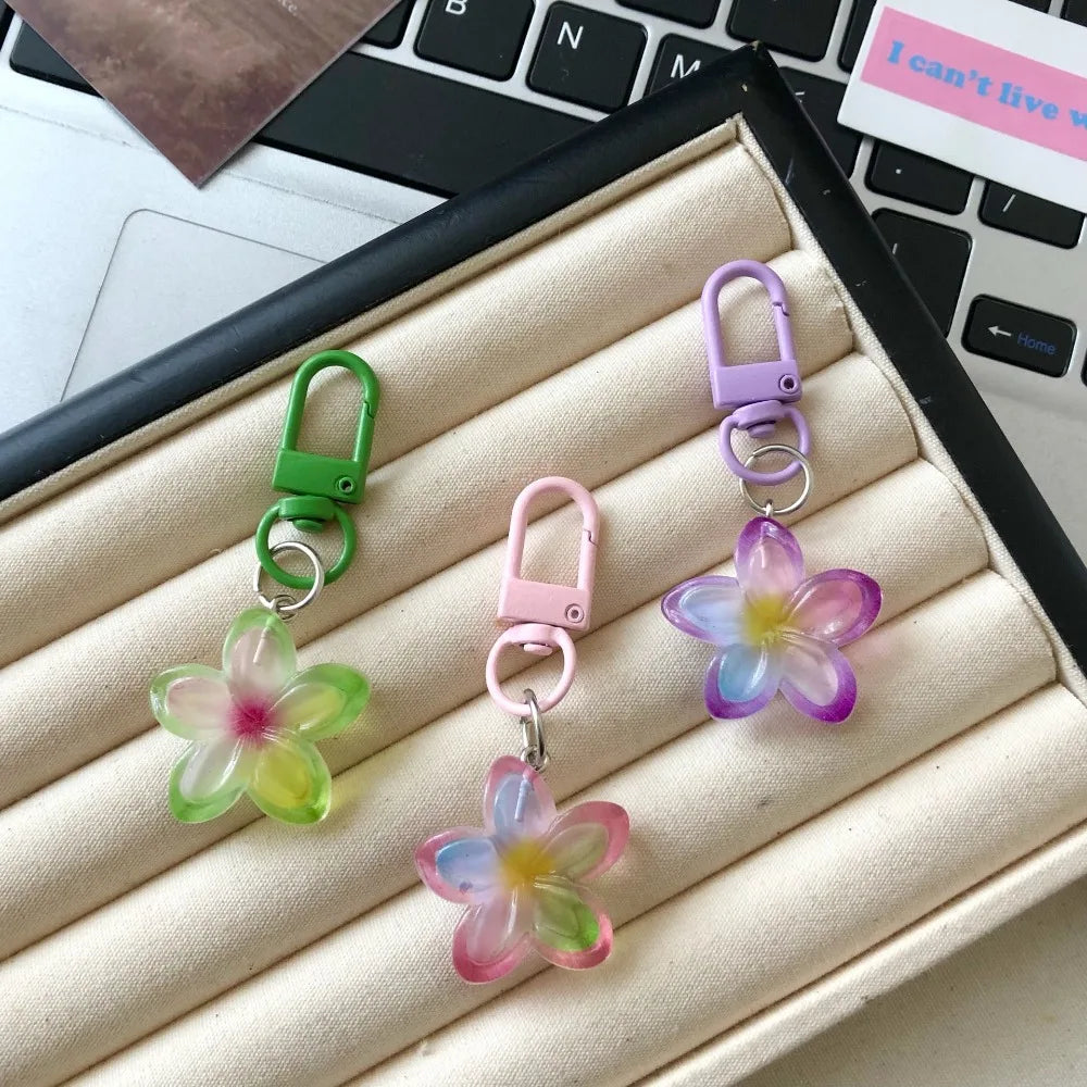 A collection of colorful resin flower keychains in green, purple, and pink hanging from metal rings.