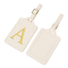 Étiquette de bagage en cuir beige clair avec un A brodé en or et une sangle en cuir.