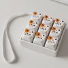 A set of white kawaii cat keycap fidget toys arranged in a rectangular holder with white elastic strings.