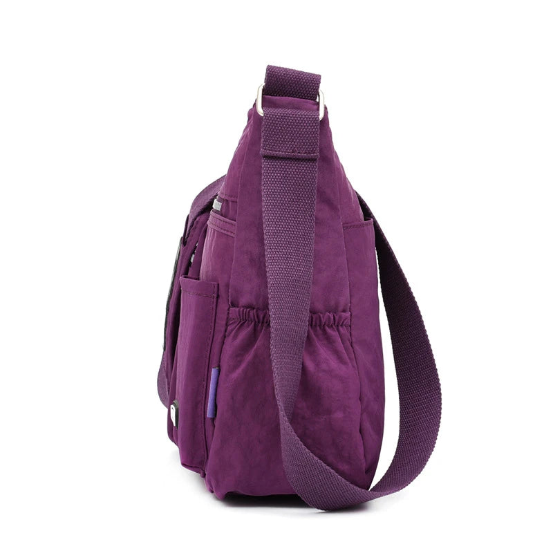 Lila wasserdichte Nylon-Crossbody-Tasche mit gepolsterter Trageleiste vor weißem Hintergrund