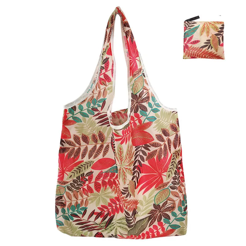 A reusable tote bag made of eco-friendly nylon featuring a floral pattern in shades of red, green, and beige.