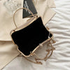 A gold glitter crossbody evening clutch bag resting on a light fabric background.