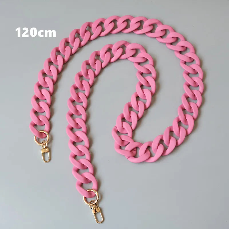 Collier en résine rose étalé sur une surface grise, mesurant 120 cm.