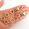 A gold-colored flower motif chain extender with a clasp is shown being held in a hand.