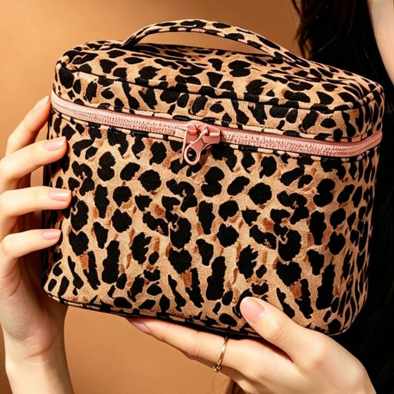Una mano sostiene una bolsa de maquillaje para viajar con estampado de leopardo marrón y negro.
