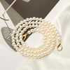 A strand of creamy white pearls used as a strap for a handbag or purse.