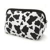 A black and white cow print cosmetic organizer bag with a zipper.