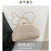 A light pink pearl embellished crossbody shoulder bag displayed against a black fabric background.