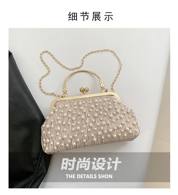 A light pink pearl embellished crossbody shoulder bag displayed against a black fabric background.