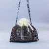 A handmade dumpling bag covered in dark silver and gold beads with a cream ribbon bow.