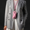 A gray blazer worn over a white top, featuring a pink leather lanyard and storage case attached to the lapel.