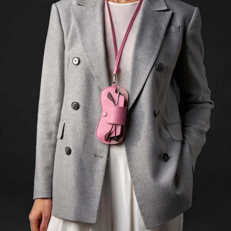 A gray blazer worn over a white top, featuring a pink leather lanyard and storage case attached to the lapel.