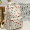 Mochila blanca con estampado floral de bayas rojas y hojas verdes, junto a un calendario.