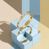A gold cuff bracelet featuring an evil eye crystal design displayed on a geometric light blue box.