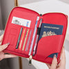A red RFID blocking travel passport holder is shown open, displaying a British passport and various documents.