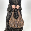 A brown leopard print crossbody shoulder bag with multiple compartments worn by a person.