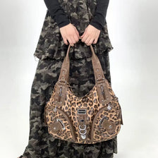 A brown leopard print crossbody shoulder bag with multiple compartments worn by a person.