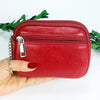 A hand holds a red PU leather mini wallet with a silver keychain against a white background.