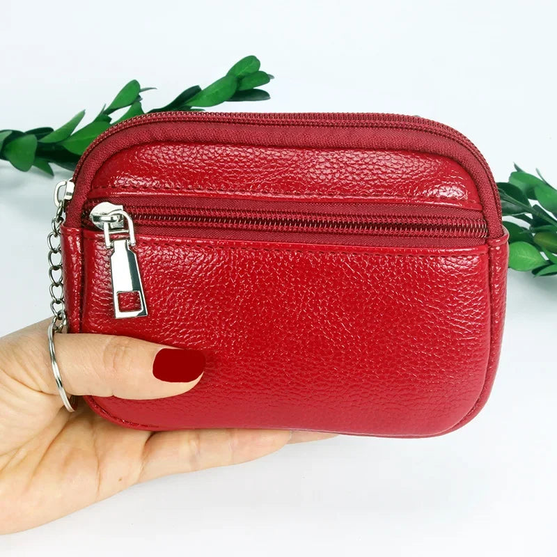 A hand holds a red PU leather mini wallet with a silver keychain against a white background.