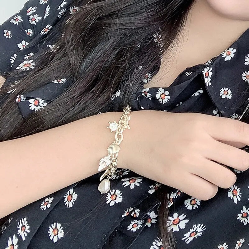 A close-up of a woman wearing an Ocean Pearl Charm Bracelet with starfish and shell accents on her wrist.