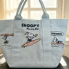 Light blue canvas shoulder bag featuring a Snoopy cartoon design with text on the front.
