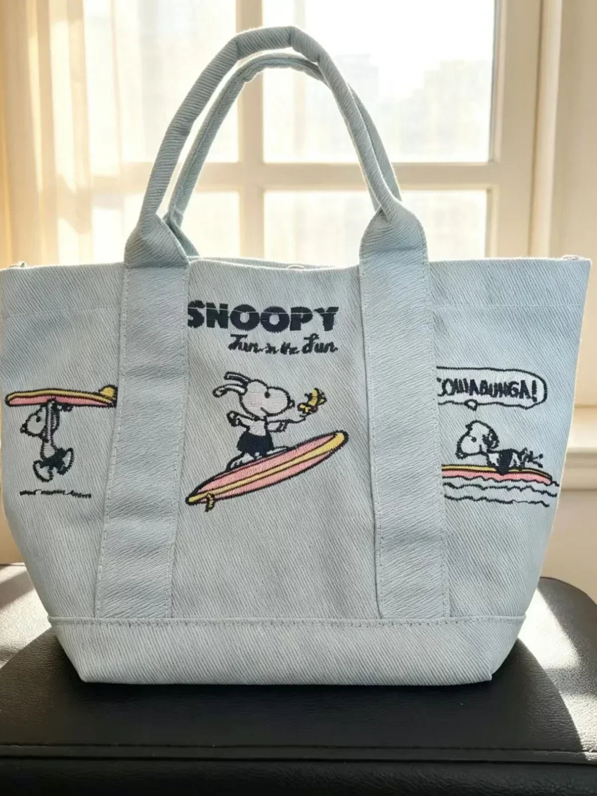 Light blue canvas shoulder bag featuring a Snoopy cartoon design with text on the front.