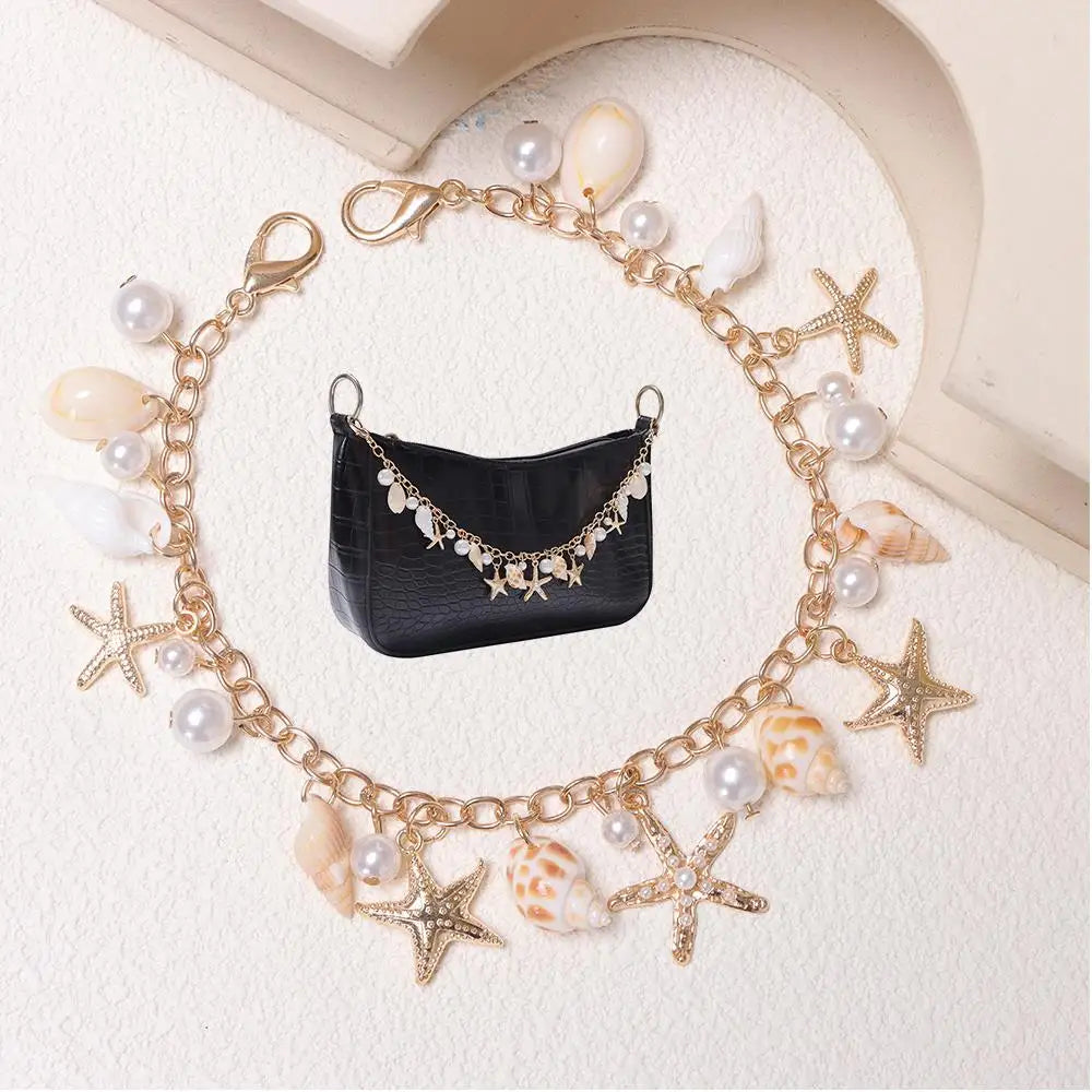 A gold layered chain featuring pearls and starfish charms draped around a black leather pouch.