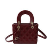 A maroon quilted diamond grid textured crossbody bag with a brown leather handle and gold hardware.