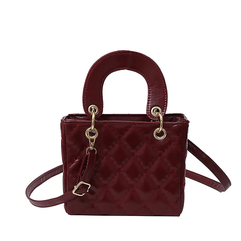 A maroon quilted diamond grid textured crossbody bag with a brown leather handle and gold hardware.