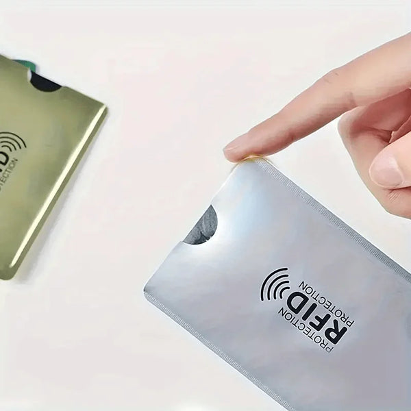 A hand is placing a silver RFID protection card sleeve onto a green card.