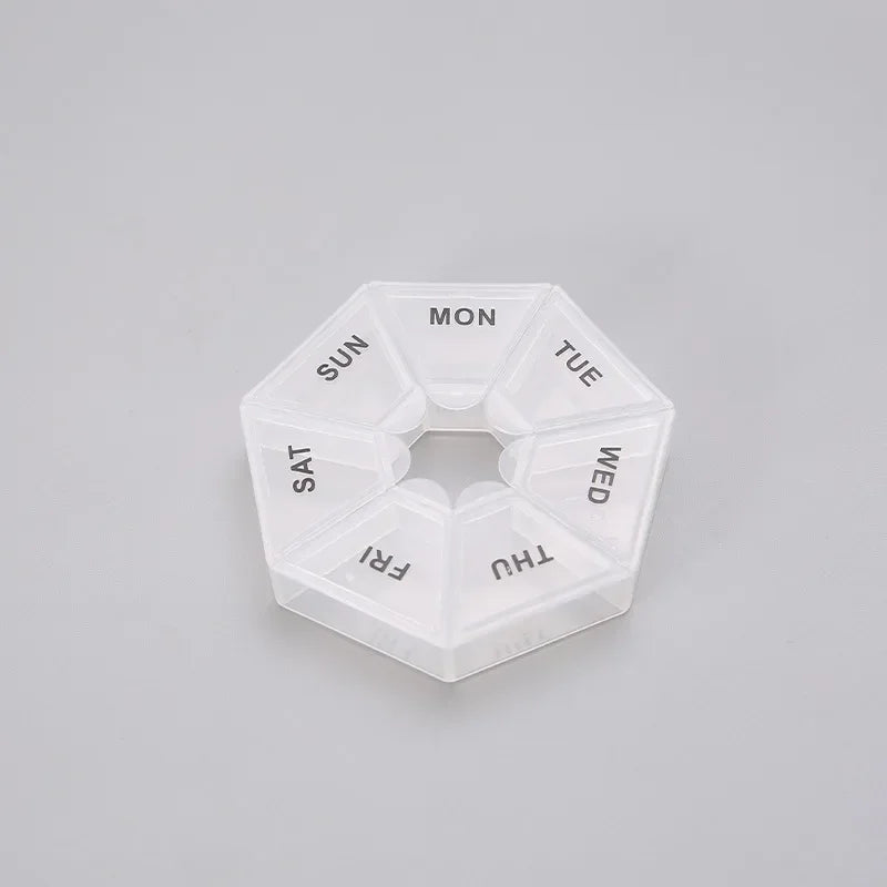 A clear, hexagonal pill organizer divided into seven sections labeled with the days of the week.