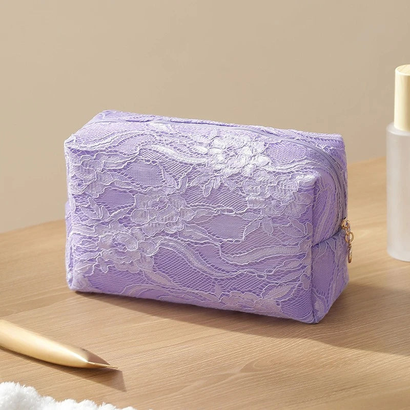 A lavender lace mesh cosmetic and jewelry organizer bag resting on a wooden surface.