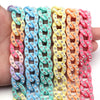 A hand holds several colorful acrylic link chains in various shades of blue, pink, yellow, and green.