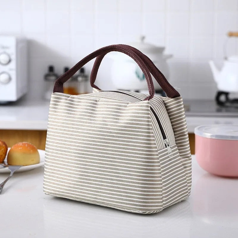 A beige and brown striped thermal lunch bag with a handle resting on a white countertop.