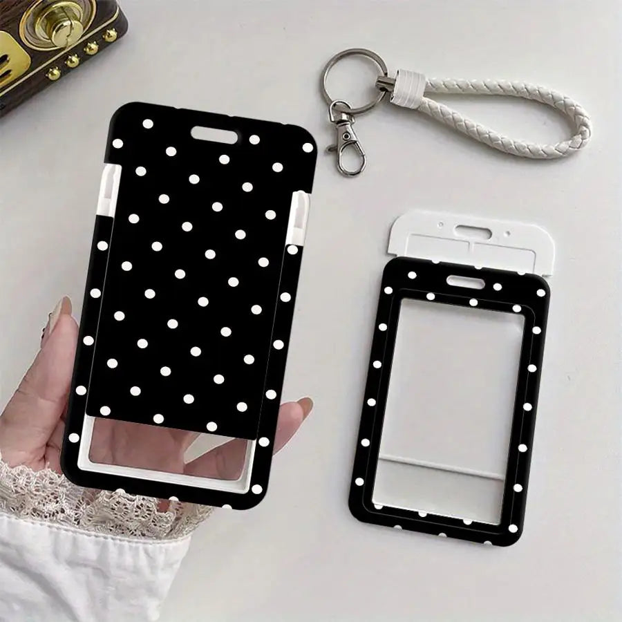 A black card holder with a clear window and white polka dots is shown next to a silver keychain and lanyard.