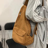 A brown canvas crossbody bag with multiple pockets is shown hanging from a gray hoodie.