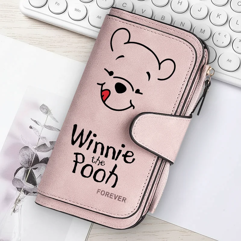 A pink zippered pouch featuring a cartoon bear face and the text Winnie the Pooh on a white background.