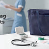 A navy blue nurse tote bag with a strap sits on a white table next to medical tools and supplies.