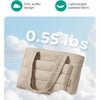 Un sac fourre-tout matelassé beige présenté contre un ciel bleu clair avec des nuages blancs.