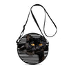 A black cat face is featured on a round black and white striped crossbody bag with a black strap.